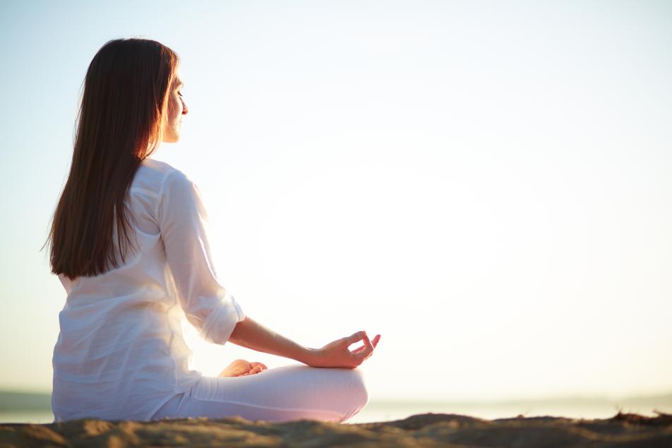 mujer relajada haciendo meditación en la playa